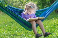 Сконцентрированный 2 старого лет чтения девушки раскрыл книгу на гамаке смертной казни через повешение в зеленом саде лета outdoo стоковая фотография rf Сконцентрированный 2 старого лет чтения девушки раскрыл книгу на гамаке смертной казни через повешение в зеленом саде лета outdoo стоковая фотография rf