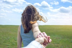 Следовать мной, привлекательной девушкой брюнет держа руку руководств в чистом зеленом поле, степь с облаками стоковое изображение rf Следовать мной, привлекательной девушкой брюнет держа руку руководств в чистом зеленом поле, степь с облаками стоковое изображение rf