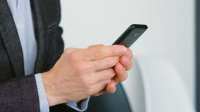 Смартфон человека отправляя SMS цифровым приложениям делая дело Смартфон человека отправляя SMS цифровым приложениям делая дело