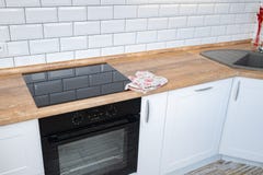 Современная мебель кухни с современным kitchenware как клобук, черная плита индукции и печь стоковые фотографии rf Современная мебель кухни с современным kitchenware как клобук, черная плита индукции и печь стоковые фотографии rf