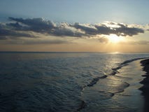 Солнце в облаках на заходе солнца морем стоковая фотография rf Солнце в облаках на заходе солнца морем стоковая фотография rf