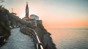 Солнце устанавливая за башней с часами в приморском городе Piran, Словении стоковое фото rf Солнце устанавливая за башней с часами в приморском городе Piran, Словении стоковое фото rf
