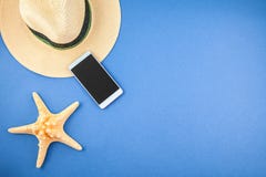 Соломенная шляпа, телефон и морская звёзда на голубой предпосылке Copyspace взгляд сверху стоковое фото Соломенная шляпа, телефон и морская звёзда на голубой предпосылке Copyspace взгляд сверху стоковое фото