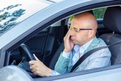 Сонный fatigued зевая вымотанный молодой человек управляя его автомобилем стоковое изображение rf Сонный fatigued зевая вымотанный молодой человек управляя его автомобилем стоковое изображение rf