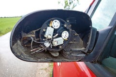 Сорванный со сломленного бортового зеркала со стеклянными отсытствиями и проводами вставляя вне на красном автомобиле стоковые фото Сорванный со сломленного бортового зеркала со стеклянными отсытствиями и проводами вставляя вне на красном автомобиле стоковые фото