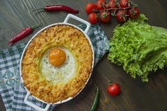 Сотейник картошки с bolognese Сотейник печеного картофеля с яйцом и заскрежетанным сыром в керамическом овальном печь листе Дерев стоковая фотография Сотейник картошки с bolognese Сотейник печеного картофеля с яйцом и заскрежетанным сыром в керамическом овальном печь листе Дерев стоковая фотография