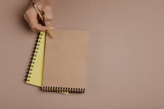 Сочинительство руки в блокноте используя ручку, на серой предпосылке стоковые изображения Сочинительство руки в блокноте используя ручку, на серой предпосылке стоковые изображения
