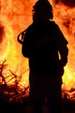 Спасатель пожарного на лесном пожаре сцены сельском Спасатель пожарного на лесном пожаре сцены сельском