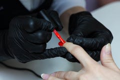Специалист по маникюра в черных заботах перчаток о ногтях рук Manicurist красит ногти с красным маникюром стоковые изображения rf Специалист по маникюра в черных заботах перчаток о ногтях рук Manicurist красит ногти с красным маникюром стоковые изображения rf