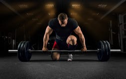 Спортсмен стоит на его колене и около бара и preparin стоковое фото Спортсмен стоит на его колене и около бара и preparin стоковое фото