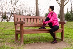 Спортсменка утомляла или отжала отдыхать на стенде на холодный зимний день на следе тренировки городского парка стоковые фотографии rf Спортсменка утомляла или отжала отдыхать на стенде на холодный зимний день на следе тренировки городского парка стоковые фотографии rf