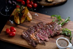 Средней прожарки куски стейка глаза нервюры мяса в лотке на прерывать деревянный стоковые фотографии rf Средней прожарки куски стейка глаза нервюры мяса в лотке на прерывать деревянный стоковые фотографии rf