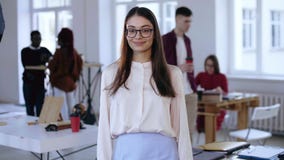 Средний портрет красивой молодой умной бизнес-леди брюнета в eyeglasses смотря камеру в ультрамодном офисе просторной квартиры акции видеоматериалы Средний портрет красивой молодой умной бизнес-леди брюнета в eyeglasses смотря камеру в ультрамодном офисе просторной квартиры акции видеоматериалы