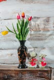 Старая деревянная предпосылка с snowdrops в бутылке и тюльпанах в v Стоковая Фотография Старая деревянная предпосылка с snowdrops в бутылке и тюльпанах в v Стоковая Фотография