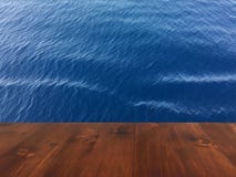 Старая таблица на голубой предпосылке моря, деревянная таблица палубы коричневого дуба деревянная стоковое фото Старая таблица на голубой предпосылке моря, деревянная таблица палубы коричневого дуба деревянная стоковое фото