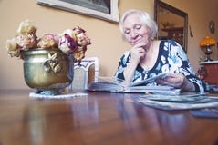 Старуха наблюдает альбом со старыми фото стоковая фотография Старуха наблюдает альбом со старыми фото стоковая фотография
