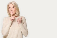 Старшая женщина делает для того чтобы hush знак указывая палец в сторону на copyspace стоковое фото rf Старшая женщина делает для того чтобы hush знак указывая палец в сторону на copyspace стоковое фото rf