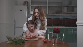 Старшая сестра учит, что более молодая сестра режет томаты для салата 2 сестры взводя курок салату овоща пока сидящ на видеоматериал Старшая сестра учит, что более молодая сестра режет томаты для салата 2 сестры взводя курок салату овоща пока сидящ на видеоматериал