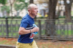 Старший человек бежать на улице города во время 21 км расстоянии марафона ATB Dnipro стоковые изображения Старший человек бежать на улице города во время 21 км расстоянии марафона ATB Dnipro стоковые изображения
