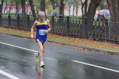 Старший человек бежать на улице города во время 21 км расстоянии марафона ATB Dnipro стоковое фото rf Старший человек бежать на улице города во время 21 км расстоянии марафона ATB Dnipro стоковое фото rf