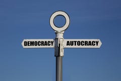 Старый дорожный знак с демократией и автократия указывая в противоположные направления Стоковое Фото Старый дорожный знак с демократией и автократия указывая в противоположные направления Стоковое Фото