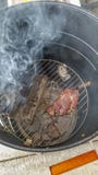 Стейк будучи закуренным внутри электрического курильщика с подносом деревянных лепешек, показывая поднимать дыма стоковая фотография Стейк будучи закуренным внутри электрического курильщика с подносом деревянных лепешек, показывая поднимать дыма стоковая фотография