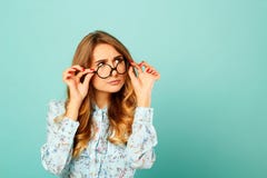 Стекла довольно заботливой девушки нося над голубой предпосылкой стоковое изображение rf Стекла довольно заботливой девушки нося над голубой предпосылкой стоковое изображение rf