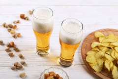2 стекла пива и закусок на белом деревянном столе Обломоки, фисташки, сухой сыр стоковые фото 2 стекла пива и закусок на белом деревянном столе Обломоки, фисташки, сухой сыр стоковые фото