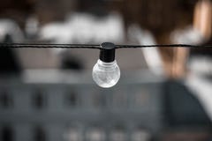 Стеклянная лампа с черным основанием на предпосылке домов Электрическая лампочка вверх r r стоковые фотографии rf Стеклянная лампа с черным основанием на предпосылке домов Электрическая лампочка вверх r r стоковые фотографии rf