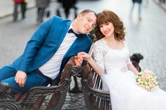 Стильная невеста пар свадьбы в белом платье и элегантном groom сидя на стенде держа руки Стоковое Фото Стильная невеста пар свадьбы в белом платье и элегантном groom сидя на стенде держа руки Стоковое Фото