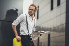 Стильный молодой бизнесмен в eyeglasses читая газету и смотря прочь стоковые фото Стильный молодой бизнесмен в eyeglasses читая газету и смотря прочь стоковые фото