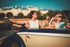 2 стильных дамы в классическом автомобиле с откидным верхом стоковое фото 2 стильных дамы в классическом автомобиле с откидным верхом стоковое фото