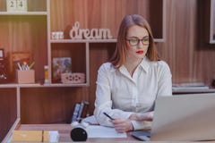 Стильная женщина работает на столе ноутбука в современном офисе стоковые фотографии rf Стильная женщина работает на столе ноутбука в современном офисе стоковые фотографии rf