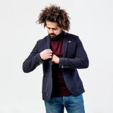 Стильный курчавый парень с бородой одетой в бургундском turtleneck, серой checkered куртке и представлениях джинсов в студию даль стоковое фото Стильный курчавый парень с бородой одетой в бургундском turtleneck, серой checkered куртке и представлениях джинсов в студию даль стоковое фото