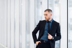 Стильный молодой бизнесмен нося современный костюм, который высокий achiever, стоя на последнем этаже офисного здания стоковое фото rf Стильный молодой бизнесмен нося современный костюм, который высокий achiever, стоя на последнем этаже офисного здания стоковое фото rf