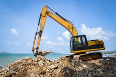 Строительная площадка камня экскаватора землекопа затяжелителя Backhoe работая на океане моря пляжа стоковое изображение Строительная площадка камня экскаватора землекопа затяжелителя Backhoe работая на океане моря пляжа стоковое изображение