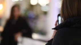 Студент gorgeus 2 привлекательный коричнев-с волосами принимает фото на smartphones в террасе места сосредоточения магазинов акции видеоматериалы Студент gorgeus 2 привлекательный коричнев-с волосами принимает фото на smartphones в террасе места сосредоточения магазинов акции видеоматериалы