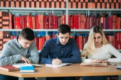 Студенты университета сидя совместно на таблице с книгами и компьтер-книжкой Счастливое молодые люди делая исследование группы в Стоковые Фото Студенты университета сидя совместно на таблице с книгами и компьтер-книжкой Счастливое молодые люди делая исследование группы в Стоковые Фото