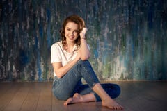 Студия сняла молодой усмехаясь девушки в джинсах и футболки сидя на поле Яркий солнечный свет, положительные эмоции стоковые фото Студия сняла молодой усмехаясь девушки в джинсах и футболки сидя на поле Яркий солнечный свет, положительные эмоции стоковые фото