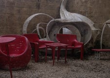 Стулья и таблица внешнего пустого кафа красные с белым современным дизайном, на маленьких камнях покрыли веранду стоковое изображение rf Стулья и таблица внешнего пустого кафа красные с белым современным дизайном, на маленьких камнях покрыли веранду стоковое изображение rf