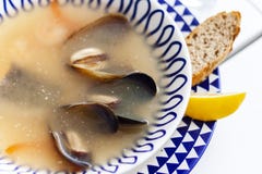 Суп морепродуктов с мидиями, креветками и рыбами в белом шаре с голубым орнаментом в ресторане стоковое фото Суп морепродуктов с мидиями, креветками и рыбами в белом шаре с голубым орнаментом в ресторане стоковое фото
