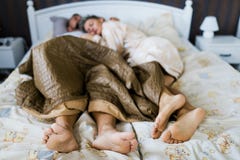 Супруг и жена спать в частично покрытой кровати совместно стоковые изображения Супруг и жена спать в частично покрытой кровати совместно стоковые изображения