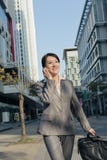 Счастливая азиатская бизнес-леди говоря на телефоне и идя на stree стоковые изображения rf Счастливая азиатская бизнес-леди говоря на телефоне и идя на stree стоковые изображения rf
