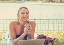 Счастливая женщина при портативный компьютер и мобильный телефон ослабляя в парке стоковое изображение Счастливая женщина при портативный компьютер и мобильный телефон ослабляя в парке стоковое изображение