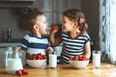 Счастливые дети брат и сестра есть клубники с молоком Стоковые Фото Счастливые дети брат и сестра есть клубники с молоком Стоковые Фото