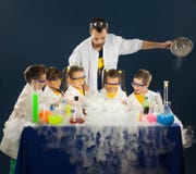 Счастливые дети при ученый делая науку экспериментируют в лаборатории стоковые изображения Счастливые дети при ученый делая науку экспериментируют в лаборатории стоковые изображения