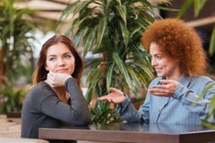 Счастливые и унылые молодые женщины говоря в кафе стоковое изображение Счастливые и унылые молодые женщины говоря в кафе стоковое изображение