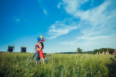 Счастливые молодые взрослые пары в влюбленности на поле 2, человек и женщина усмехаясь и отдыхая после катания велосипеда стоковое фото rf Счастливые молодые взрослые пары в влюбленности на поле 2, человек и женщина усмехаясь и отдыхая после катания велосипеда стоковое фото rf