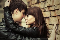 Счастливые молодые пары в влюбленности на кирпичной стене Стоковые Изображения Счастливые молодые пары в влюбленности на кирпичной стене Стоковые Изображения