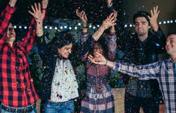 Счастливые друзья имея потеху среди confetti партии стоковые изображения rf Счастливые друзья имея потеху среди confetti партии стоковые изображения rf